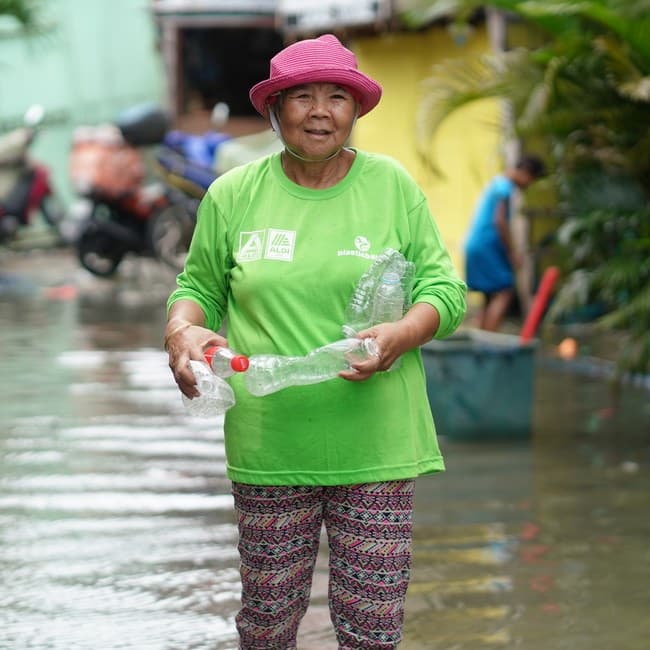 A Plastic Bank collection member gathering plastic bottles from a flooded street in the Philippines