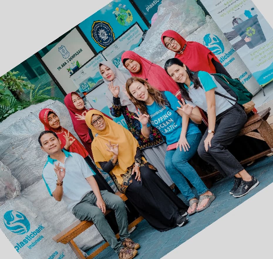 Community members and Plastic Bank staff gathered in front of sacks of collected plastic at a neighbourhood collection point