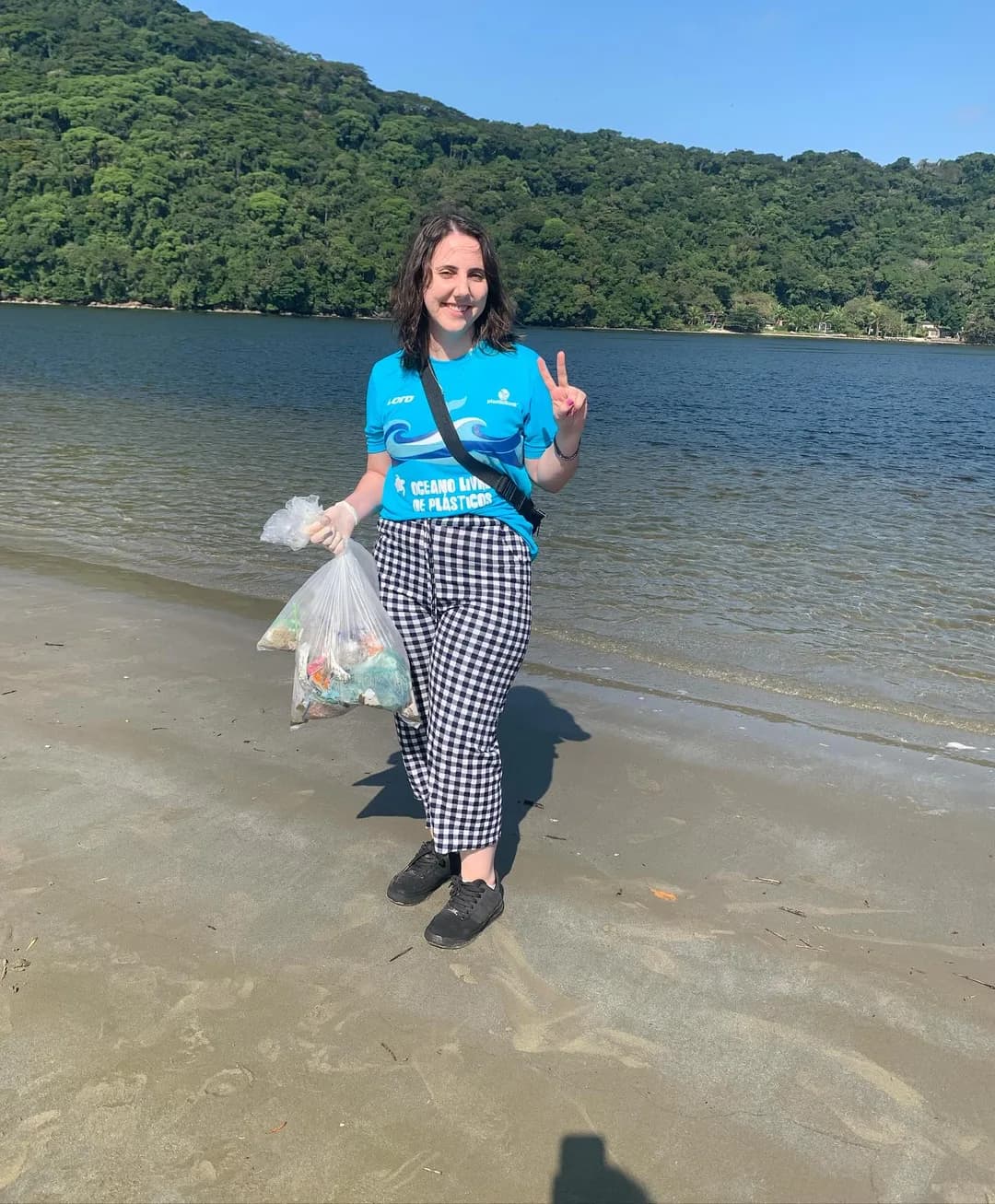 Letícia Caliani on a beach, gathered plastic in hand