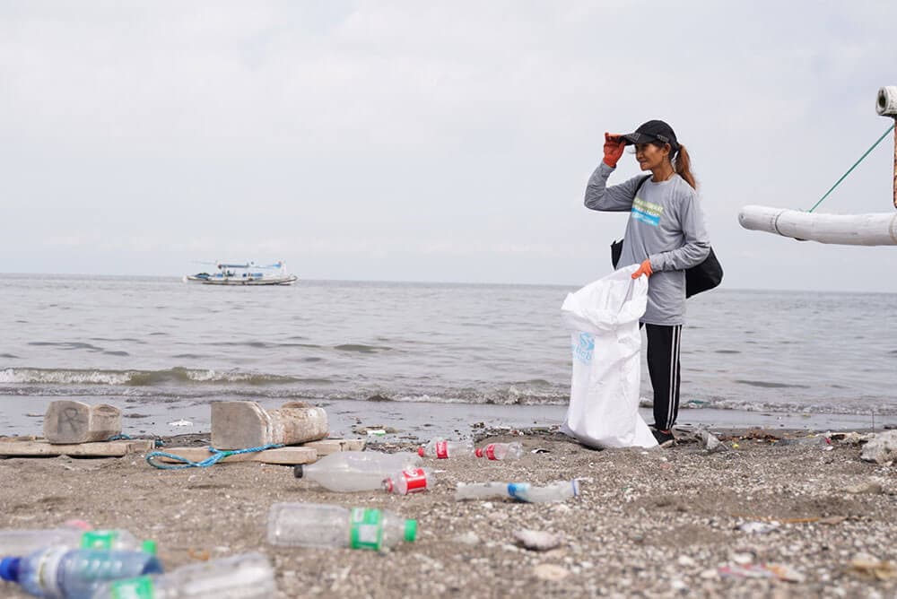 Plastic Bank collection member in the Philippines collecting plastic waste by the beach.