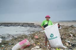 A person standing on a beach heavily littered with plastic waste.