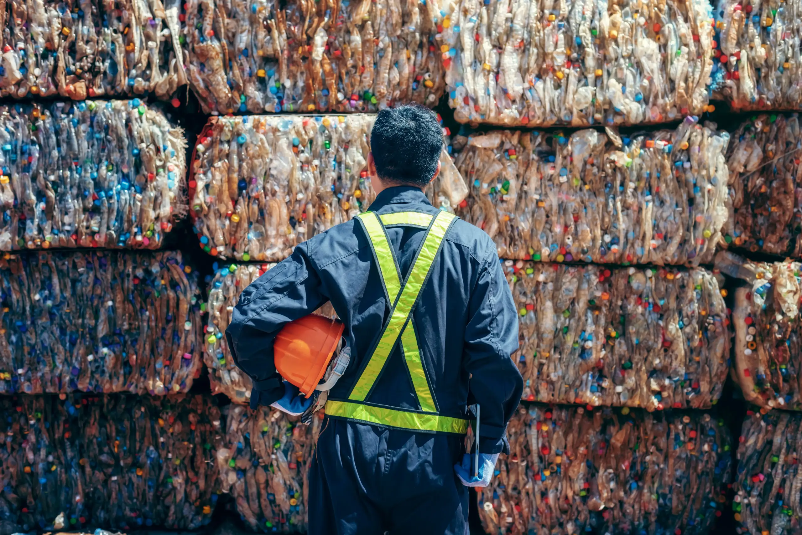 A man looking at bales of recycled plastic