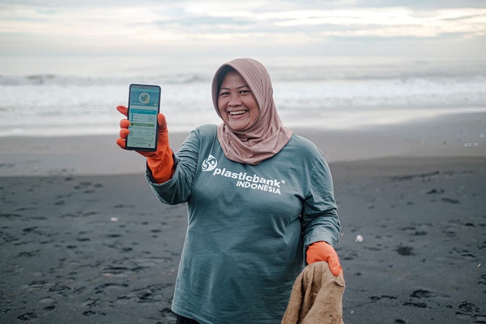 Slami shows Plastic Bank application on the beach in Bali, after she collects plastic waste.