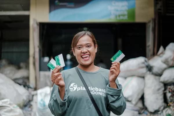Plastic Bank member Sulistia Karini holding member cards at a collection branch in Indonesia