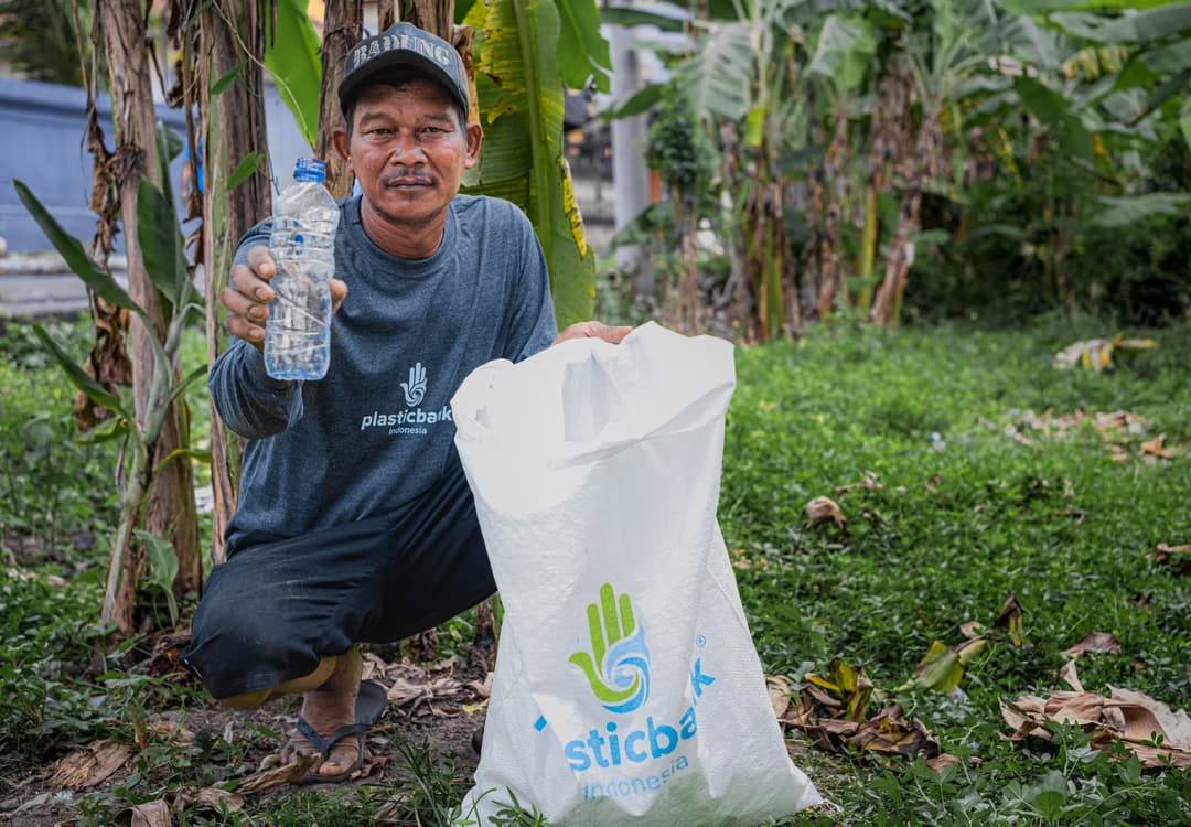 Plastic Bank member collecting and showing a plastic bottle