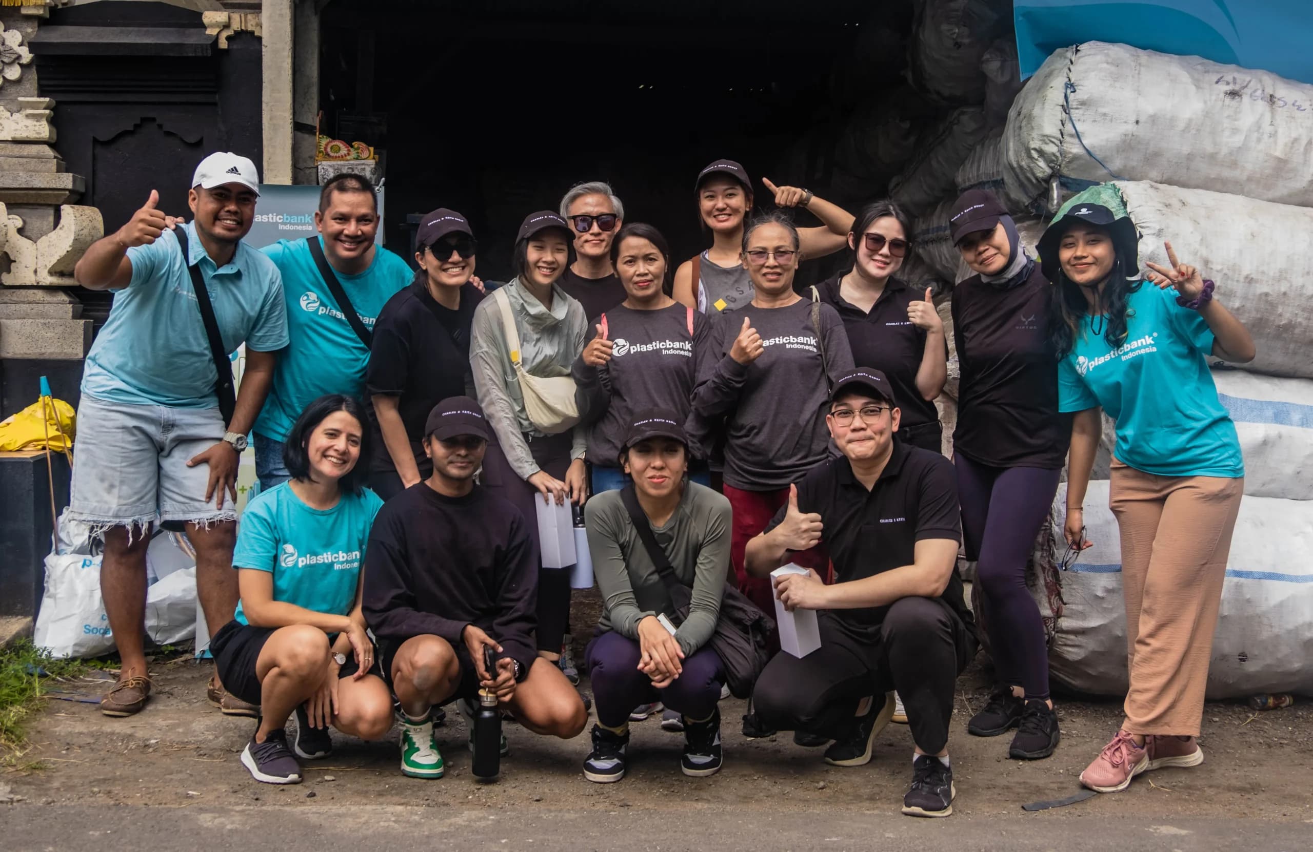 A group of approximately fifteen individuals, likely the Charles & Keith & Plastic Bank team, are gathered outdoors for a photo.